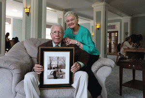 Marcy and Juney Morris, holding a photo of themselves in front of Virginia Hall, visit Virginia lounge as students study nearby.